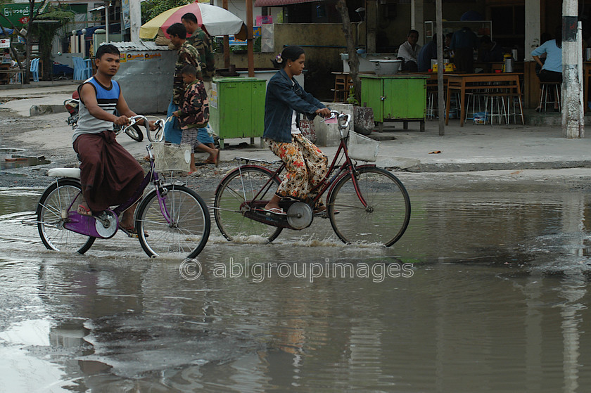 Burma - 00648 
 Cycle through a puddle Central Manadalay - 
 Keywords: women, bicycle, Bagan, Man, Asia, Myanmar, Woman, female, Burma, land transportation