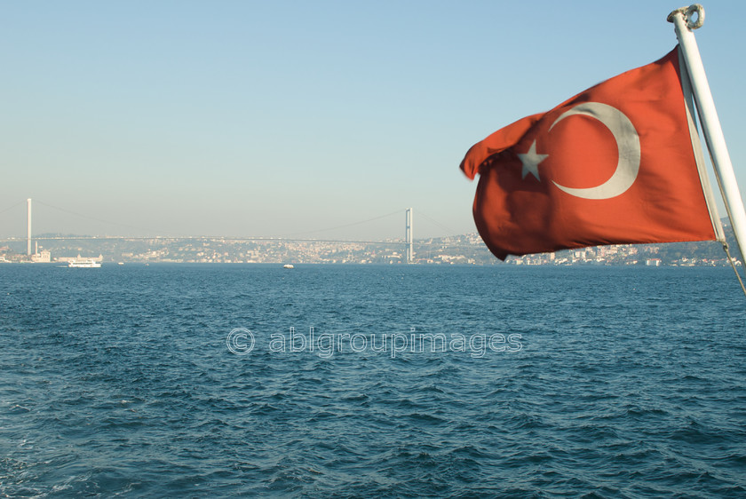 Turkey-351 
 Bosphorus Bridge from Boat Besiktas to Eminonu 
 Keywords: Asia, Bosphorus, bridge, Day, Europe, Flag, Imagefile-Gallery, INFRASTRUCTURES, Istanbul, Mediterranean, suspension bridge, transportation, Turkey, Whitewall-Gallery