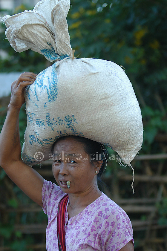 Burma - 01492 
 Inle Lake - lady smoking a Cheroot (cigarette) whilst carrying a sack of Tobacco leaves on her head 
 Keywords: women, Portrait, female, Asia, Myanmar, Burma, Woman