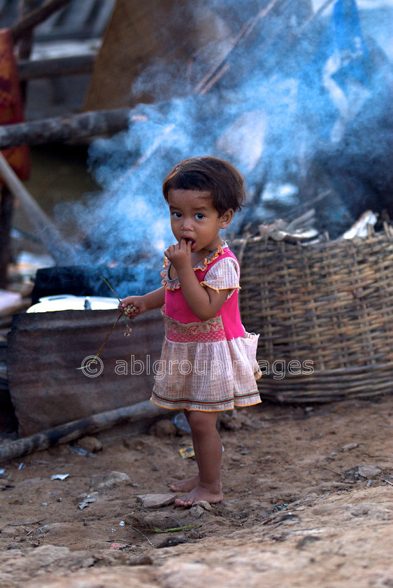 Cambodia -452 
 Young girl waiting for dinner cooking in the background 
 Keywords: Asia, Cambodia, Child, Girl, , People, Siem Reap