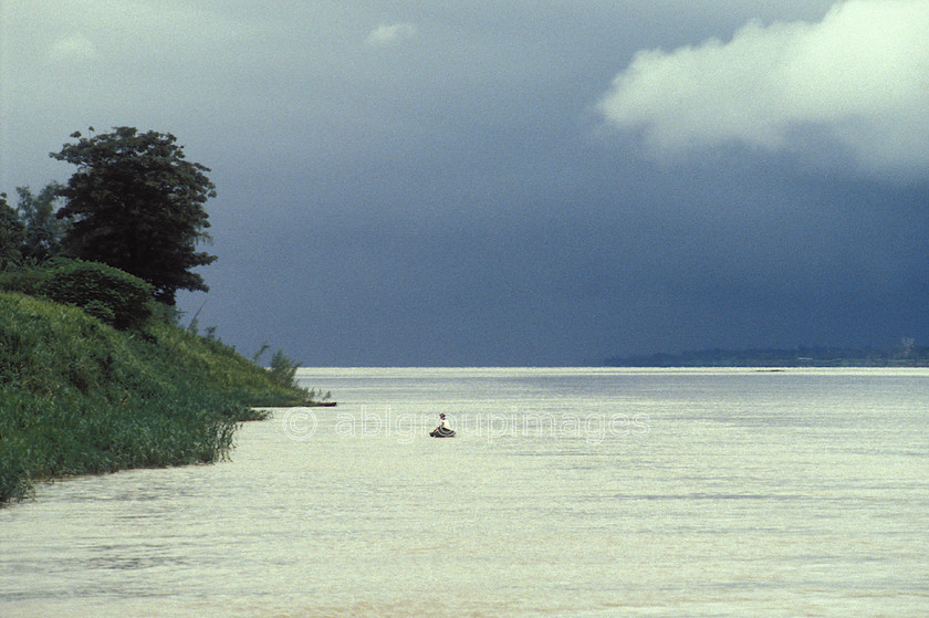 BRA379 
 Amazon River with man in canoe 
 Keywords: canoes, Brasil, storm clouds, canoe, Day, sky, cloud, storm cloud, Landscape, water, boats, South America, water transportation, river, Brazil