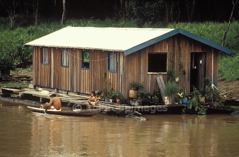 BRA370 
 Floating house hut on the Amazon river with man in canoe 
 Keywords: barges, Brasil, water transportation, Day, Brazil, canal boats, Landscape, Amazon, South America