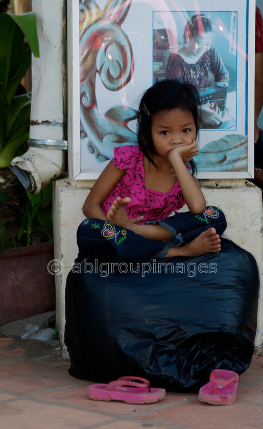 Cambodia -481 - Version 2 
 Portrait of a young girl on large bag 
 Keywords: Asia, Cambodia, Child, Girl, , People, Siem Reap