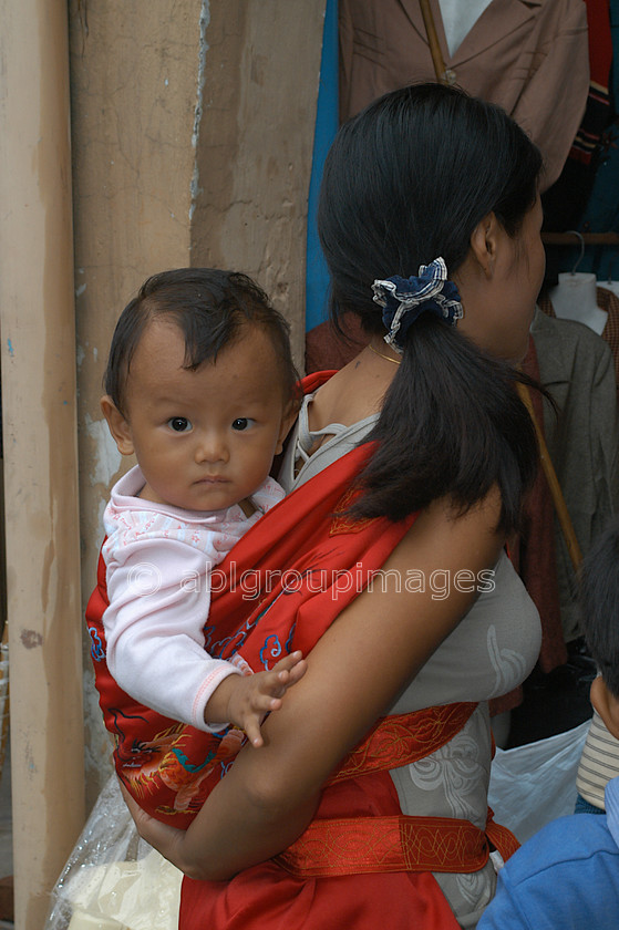 Burma - 00626 
 Mother carrying child, Central Manadalay - 
 Keywords: female, mother, Asia, Woman, Baby, Bagan, Myanmar, Portrait, Burma, parent, women