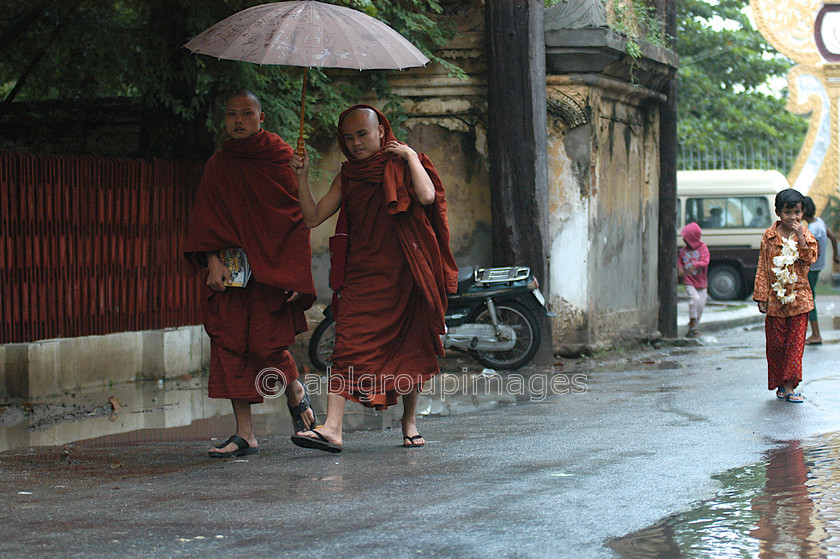 Burma - 00914 
 Monks walking with umbrella in the rain, Central Manadalay - Shwenandaw Monastry and area 
 Keywords: monk, Asia, rain, Myanmar, male, Burma, Man, religion, Bagan